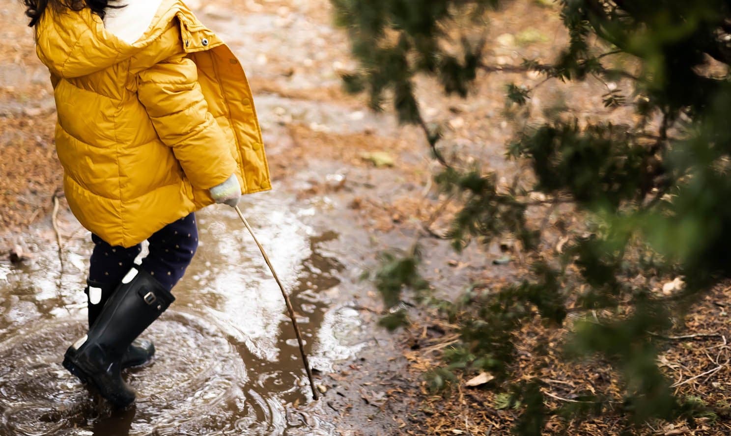 A child plays in a puddle during a rain shower