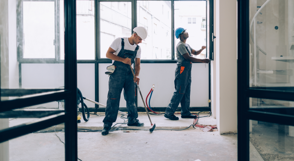 Two construction workers clean and prep the work area.